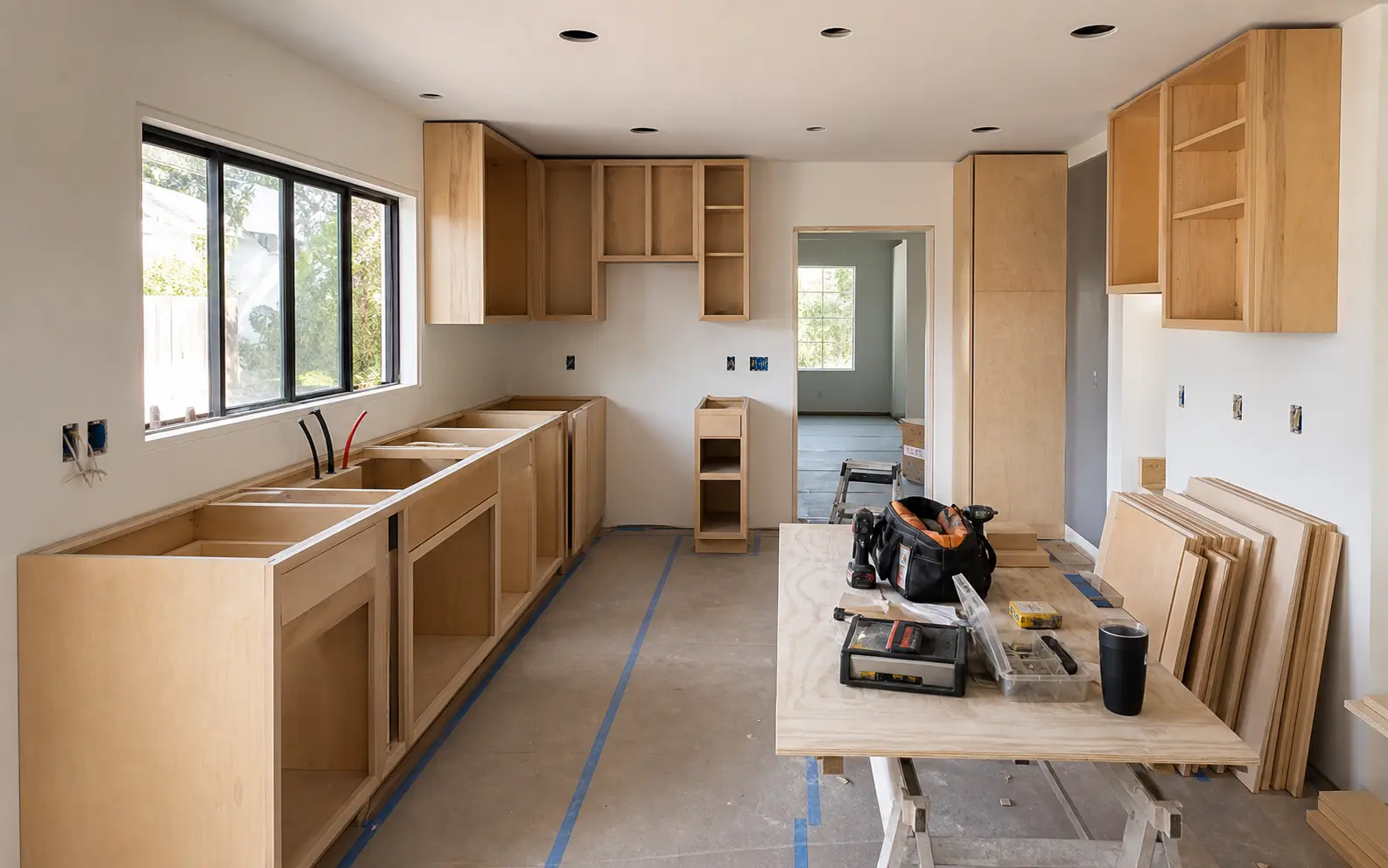 Kitchen remodel in progress with cabinet boxes, protected floors, and organized installation materials
