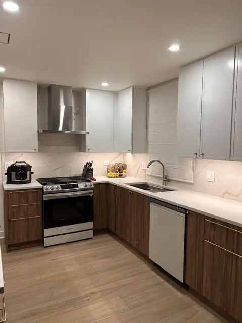 Kitchen after remodeling with white upper cabinets, walnut lower cabinets, quartz counters, and stainless steel appliances