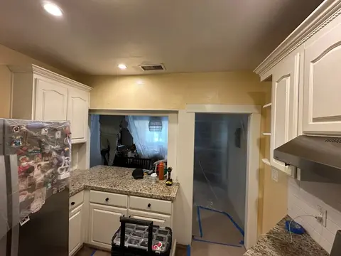 Kitchen after remodeling with white cabinet fronts, granite counters, and updated recessed lighting