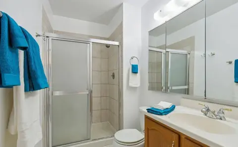 Bathroom before remodeling with a framed shower enclosure, tiled floor, and original wood vanity