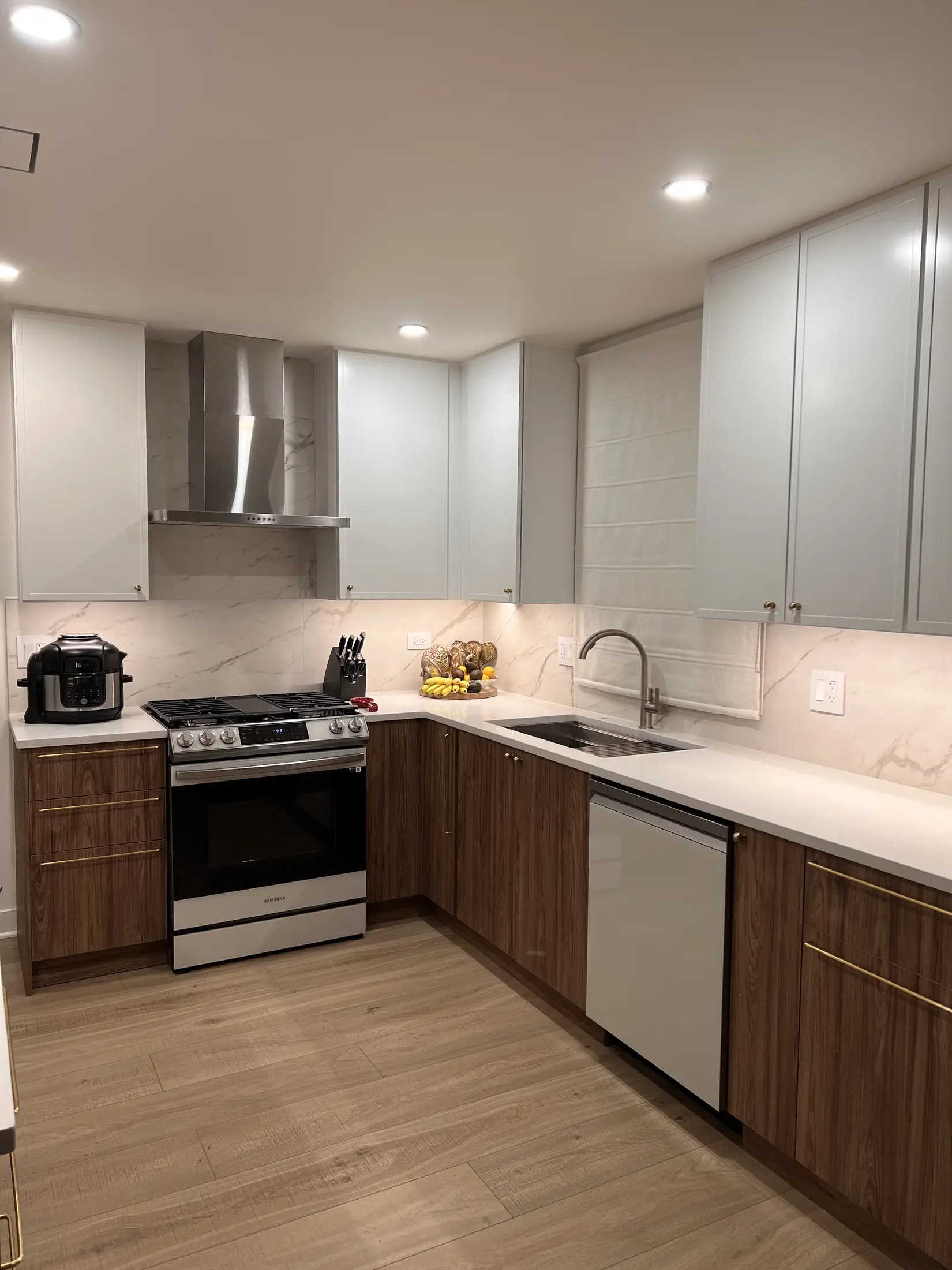 Renovated kitchen with warm lower cabinets, light upper cabinets, and new lighting